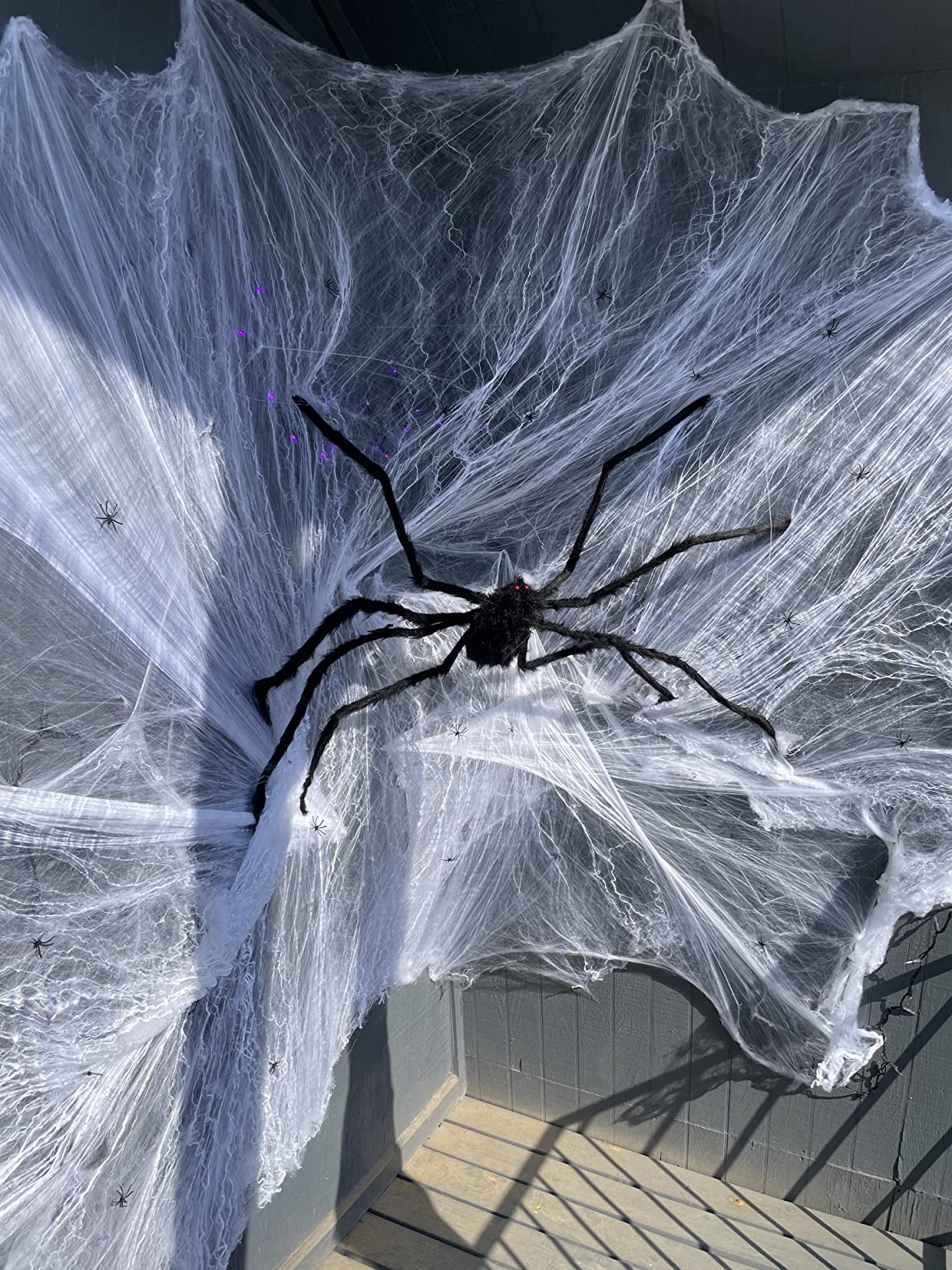 Giant fuzzy black Halloween spider decoration on a porch web